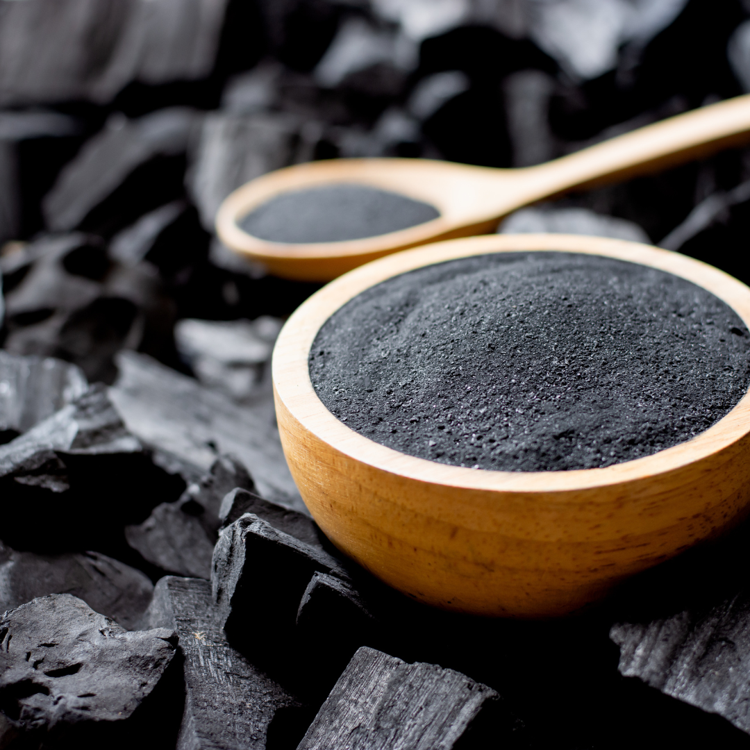 Wooden bowl holding activated charcoal powder sitting on charcoal bricks