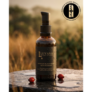 Luyana Skincare African Black Soap with Rosehip bottle on a stone surface with a blurred natural background