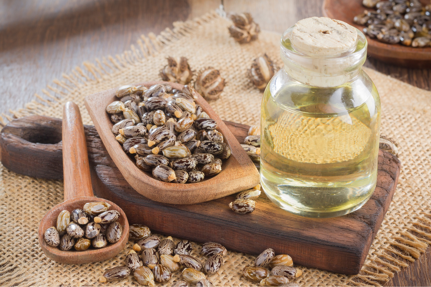 Castor oil next to a wooden board holding castor seeds