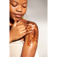 Woman spreading coffee scrub on her shoulder