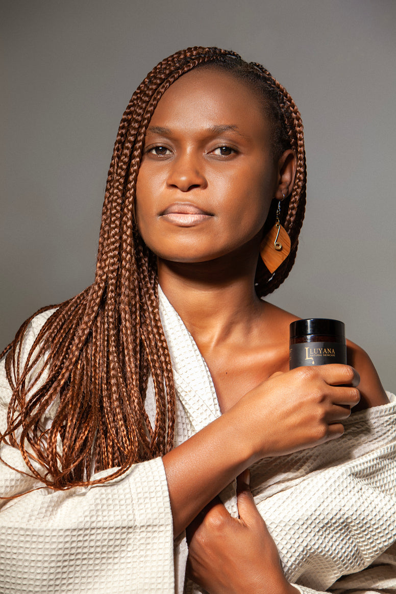 Woman holding a jar of Luyana Skincare with a gray background