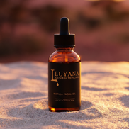 Luyana Skincare Marula Oil in a dropper bottle on sand with sunset background.