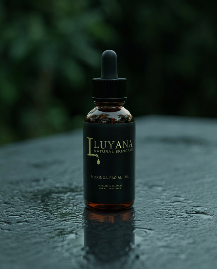 Bottle of Luyana Skincare Moringa Facial Oil on a dark surface with a blurred green background