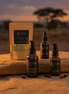 Luyana Skincare Sacred Glow Ritual collection products on a stone surface with a sunset landscape in the background