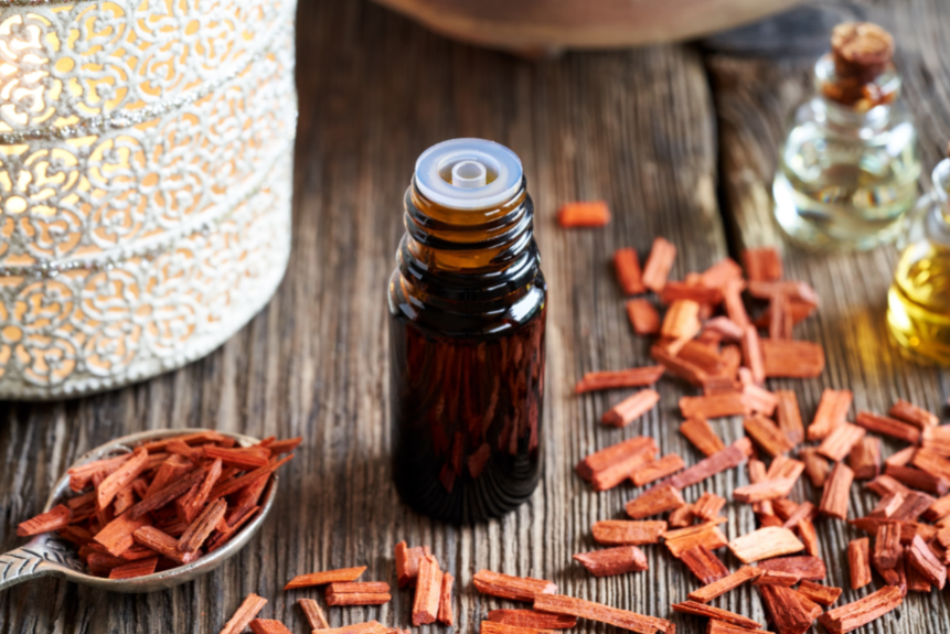 Small amber glass bottle containing sandalwood oil and surrounded by pieces of sandalwood shavings