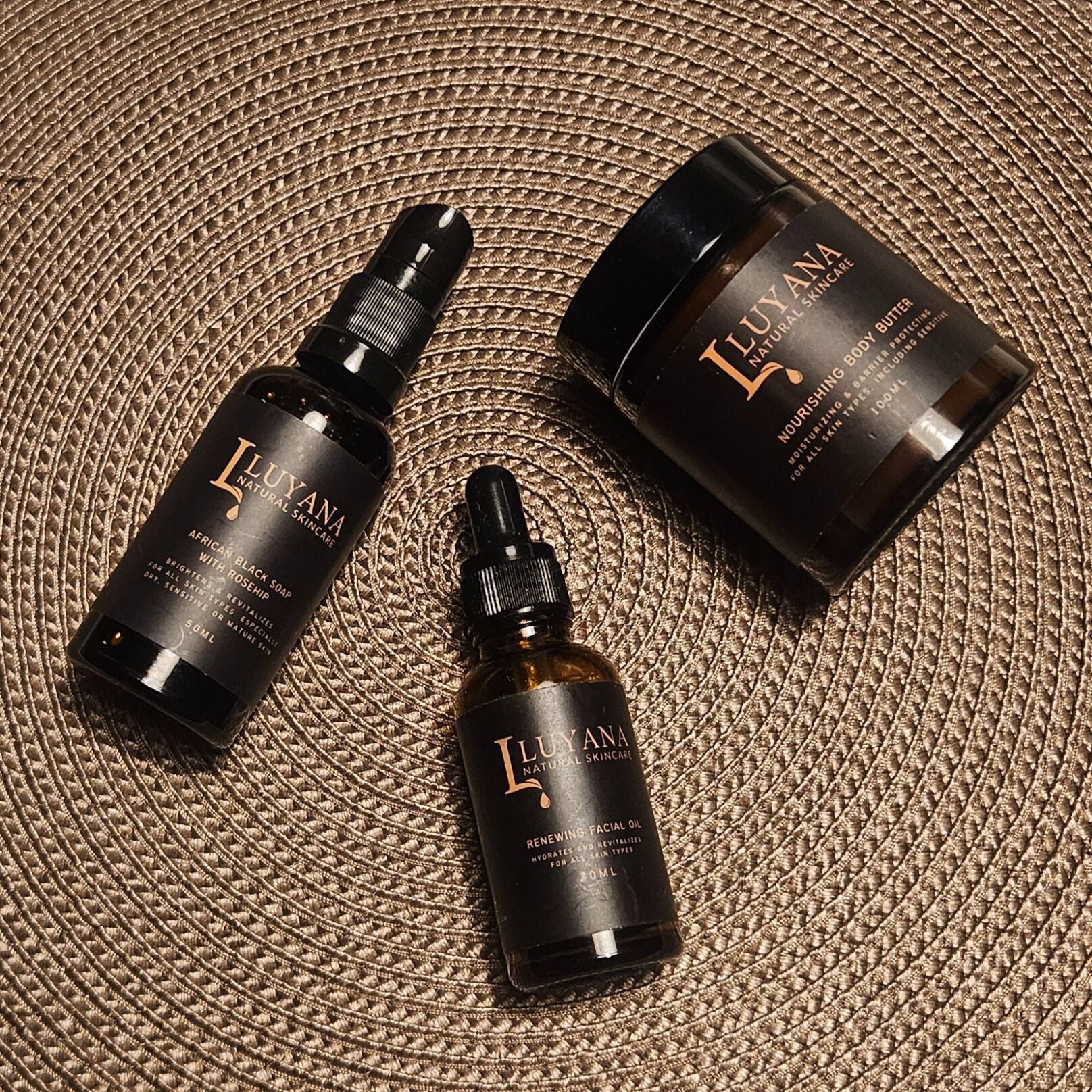 Three dark glass skincare products with 'Luyana' branding on a textured surface.