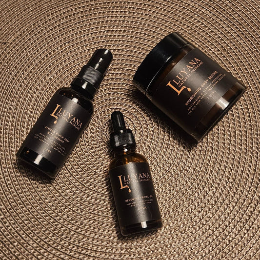 Three dark glass skincare products with 'Luyana' branding on a textured surface.